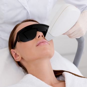 partial view of young woman receiving laser hair removal epilation on face in salon